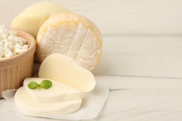 Different dairy products and basil on white wooden table, closeup. Space for text