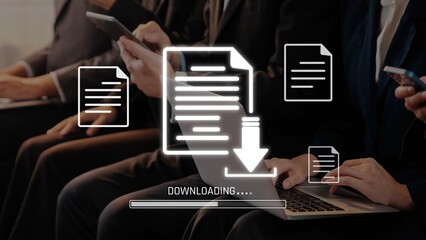 A group of business professionals are focused on downloading digital documents using laptops and mobile devices in a contemporary office environment, showcasing teamwork and technology. Raster