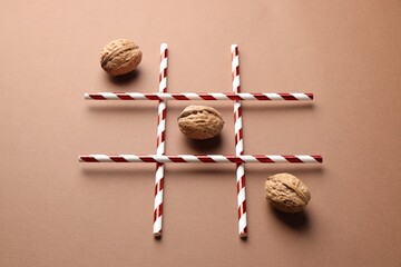 Tic tac toe game made with walnuts on beige background