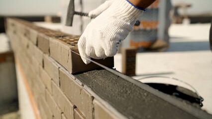Worker laying brick wall with mortar and level string