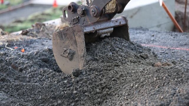 Excavator digging into gravel fill