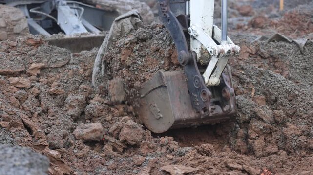 excavator bucket digging mud and gravel fill