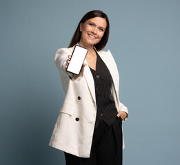 Businesswoman holding smartphone, showing empty screen on blue background.
