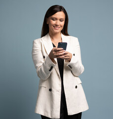 Smiling middle aged businesswoman using smartphone mobile phone online app for work isolated on blue background