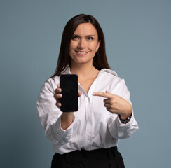 Businesswoman holding smartphone, showing empty screen on blue background.