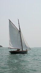 Fototapeta premium Voilier traditionnel en bois naviguant sur une mer calme avec voiles blanches