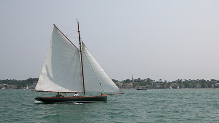 Voilier traditionnel en bois naviguant sur une mer calme avec voiles blanches