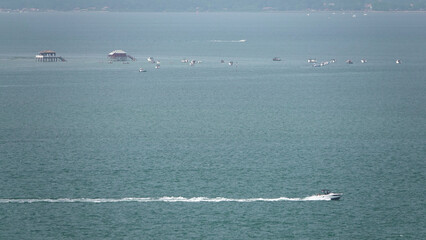 Bateau à moteur rapide laissant un sillage avec vue sur les Cabanes Tchanquées du Bassin...
