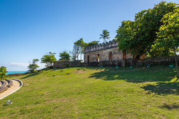 Historic El Faro lighthouse in Puerto Plata, Dominican Republic, viewed from below on a sunny day, with blue sky, green trees and iconic iron structure symbolizing Caribbean heritage