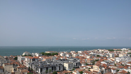 Fototapeta premium Vue panoramique aérienne de la ville côtière d'Arcachon avec toits rouges et l'océan à l'horizon