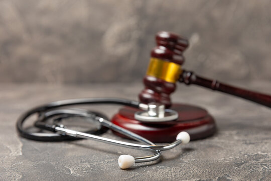 A stethoscope and hammer on a desk. Medical malpractice, personal injury lawyer, and healthcare legal aspects concept.Lawyer.Legal definition of medical negligence. Law concept.Healthcare and Medicine