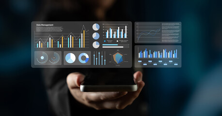 A professional holding a smartphone displaying dynamic charts and graphs, illustrating data management and analytics in a modern business environment. Gantry