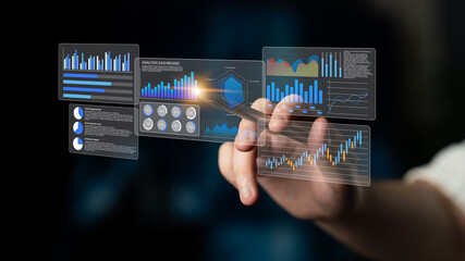 A hand holding a stylus interacts with a transparent digital dashboard showcasing colorful data visualizations and analytics charts on a dark background for business insights. Gantry