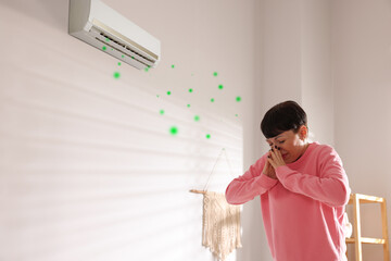 Woman covering her nose because of bad smell from air conditioner in room. Bacteria flying from...