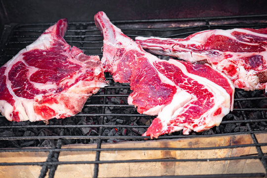 High quality raw beef steaks placed on a charcoal grill ready for cooking highlighting the high protein nutritional value of meat amidst global food security and climate change concerns today.