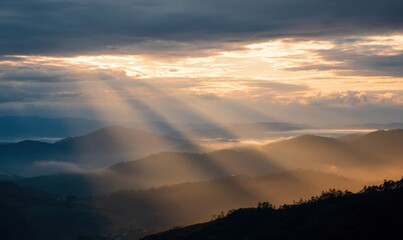 Scenic sunrise over misty mountain landscape with sun rays and clouds
