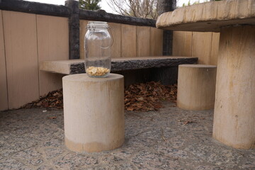 A jar is sitting on a cement bench. The bench is empty