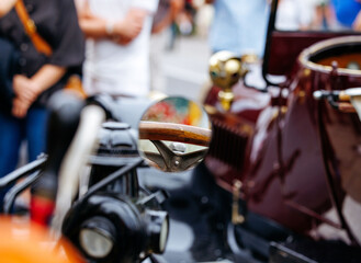 Close-up of vintage car mirror at classic auto show with crowd in background