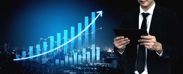 A businessman in a suit uses a tablet while standing against a city skyline, showcasing a digital financial chart that illustrates growth and progress. Scalp