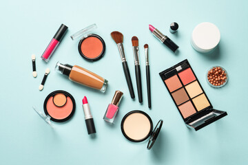 Obraz premium Beauty products on blue background. Cosmetic palette, brushes, cream and lipsticks. Top view.