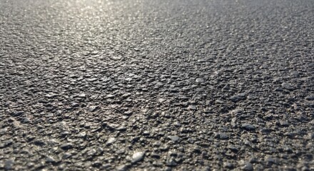 Close-up view of textured asphalt surface under sunlight  