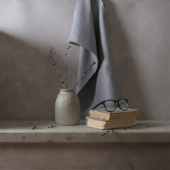 Still life with a gray drapery, a vase, glasses on a light wooden table