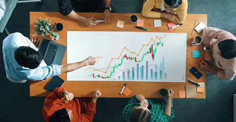 A diverse team collaborates to analyze financial data and market trends, using charts and graphs to enhance their strategic meeting in a modern workspace. Scalp