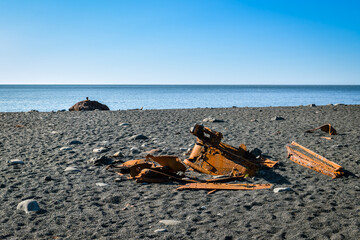 Small metal pieces of shipwreck on black pebble beach on Iceland