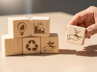 Hand stacking wooden blocks with eco icons like CO2 reduction, tree, and savings symbols on a white background, representing sustainable development