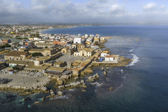 Aerial view of the sun-kissed buildings and the Piazza Regina Margherita meeting the turquoise sea, Marzamemi, Sicily, Italy.