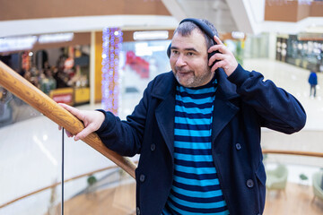 Man Listening with Headphones Indoors. Person listens to sound while standing near glass surface...
