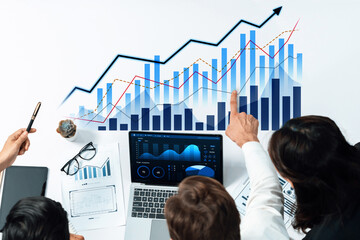 Diverse business team collaborates on financial analysis using charts and a laptop, showcasing modern workspace dynamics and data-driven decision-making strategies. Scalp
