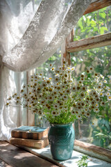 Summer sunny still life with a vase of daisies on the wooden window of an old house