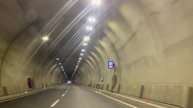 A view from inside a vehicle passing through a modern, well-lit highway tunnel. Dynamic driving scenes themed around transportation, infrastructure, speed, and modern engineering.