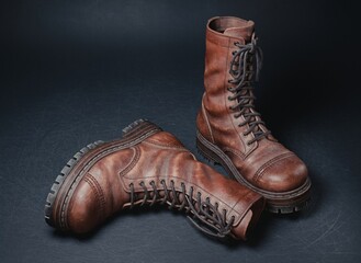 3d rendering of retro brown leather boots on a dark background. High vintage lace-up design with realistic scuffs and a worn-out look. Detailed heavy sole with tread patterns. Footwear concept.
