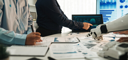 A dynamic workspace shows business professionals analyzing data on screens with advanced technology. The team discusses strategies and innovative solutions for business growth.Noogenesis