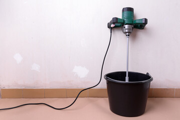 Electric drill mixer and mortar bucket on construction site