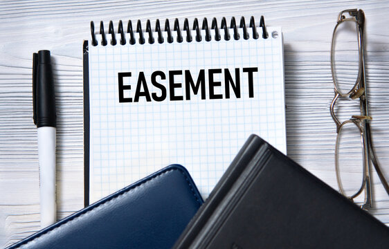 EASEMENT - word in white paper on the background of a diary, glasses and pen