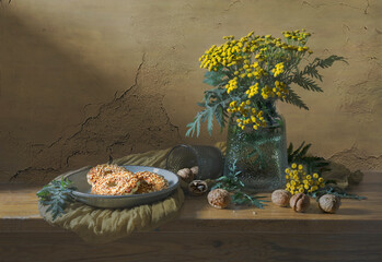 Still life in yellow and brown tones with a bouquet of yellow flowers, walnuts and confectionery