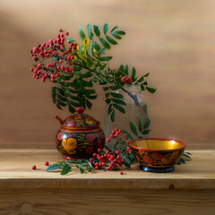 Still life with red rowan berries and wooden utensils painted with Khokhloma style