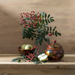 Still life with red rowan berries and wooden utensils painted with Khokhloma style