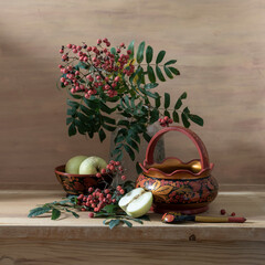 Still life with red rowan berries and wooden utensils painted with Khokhloma style