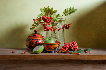 Still life with red rowan berries and wooden utensils painted with Khokhloma style