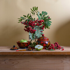 Still life with red rowan berries and wooden utensils painted with Khokhloma style