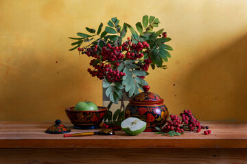 Still life with red rowan berries and wooden utensils painted with Khokhloma style