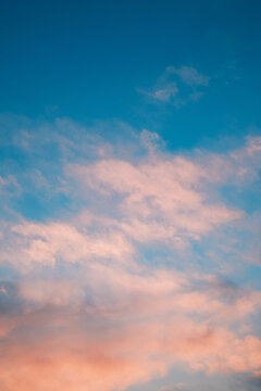 Soft pastel cloudscape at sunset, dreamy blue and pink sky background, calm atmospheric nature scene