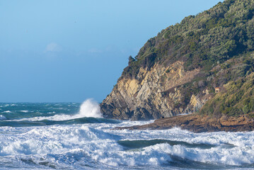 Vibrant seascape featuring a steep rocky cliff, foaming waves, and a blue horizon, Baratti, Tuscany, Italy