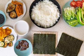 Sushi preparation ingredients: rice, seaweed, vegetables, and toppings displayed on table