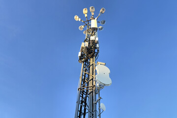 Communications tower with antennas and dishes against clear blue sky