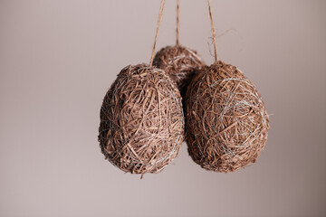 Pair of natural straw Easter eggs hanging on background
